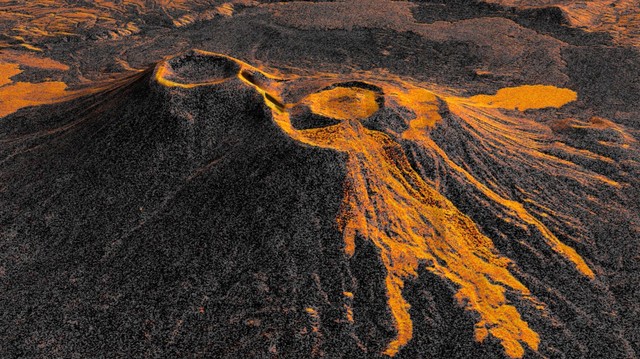 A still image from an animated view swoops down on a three-dimensional map of the region of Russia’s Kamchatka Peninsula. It settles on a view of a two volcanoes arranged left and right, shown in shades of dark and light orange.