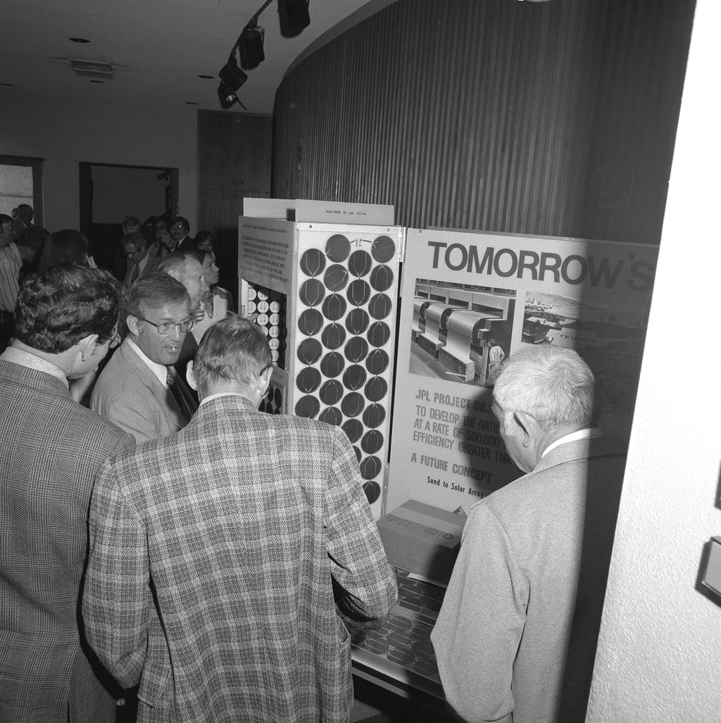 Men in suits standing around a photovoltaics display