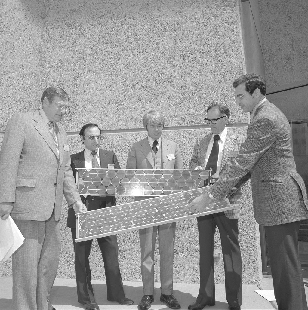 Five men in suits holding two photovoltaic solar panels