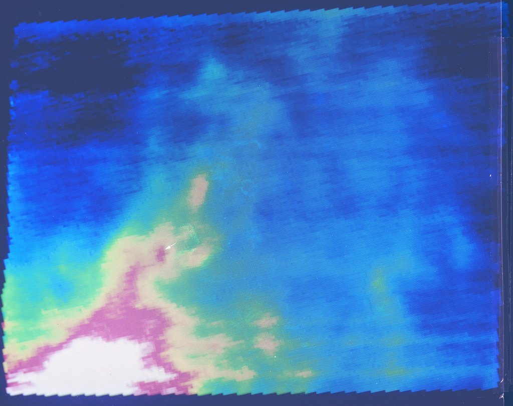 False-color infrared image from IRAS showing a region of space with thermal intensity displayed in blue, green, yellow, and pink hues.