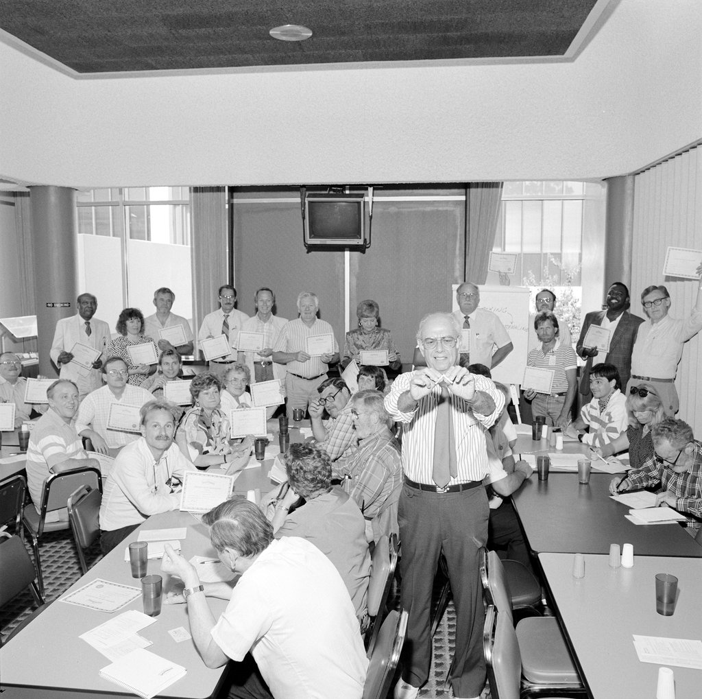 Man breaking cigarette with both hands surrounded by group of people