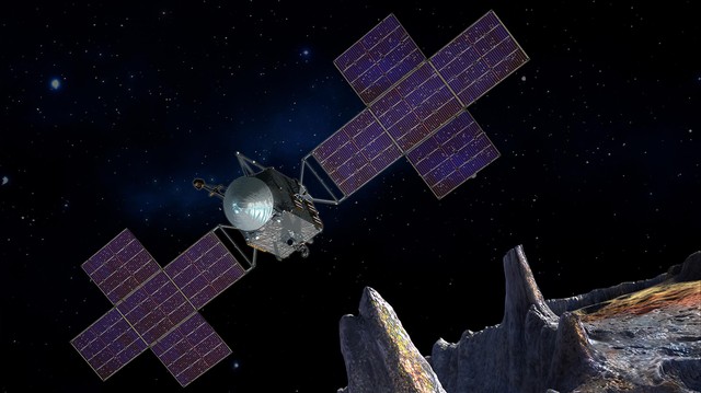 An illustration depicts the silver-colored Psyche spacecraft with two cross-shaped bluish solar panel arrays flying through outer space above a rocky, cratered asteroid.