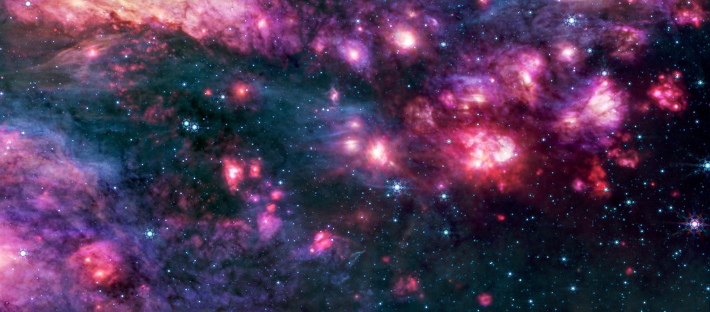 Webb’s MIRI instrument shows the Sagittarius B2 region in mid-infrared light, with warm dust glowing brightly. Only the brightest stars emit strongly enough to appear through the dense clouds as blue pinpoints.