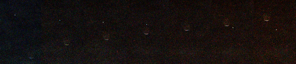 A grainy black image showing a horizontal sequence of seven faint crescent shapes evenly spaced from left to right. A tiny bright white dot moves diagonally from the upper left to the lower right, appearing to pass behind the crescent shapes.