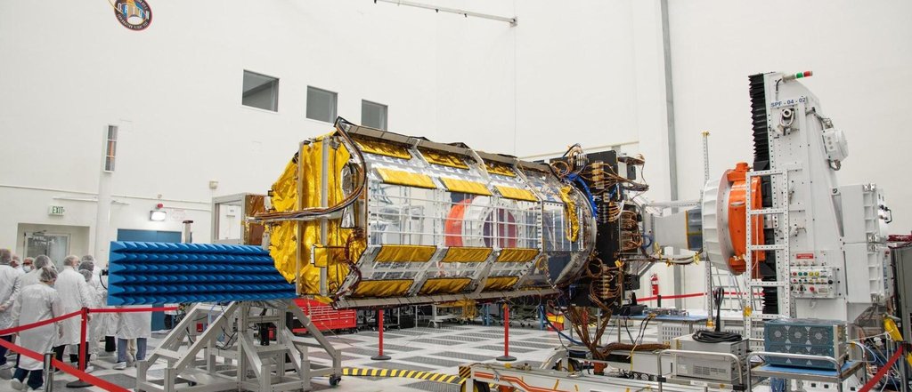 Partially assembled satellite, about the size of a pickup truck, sits in NASA cleanroom facility