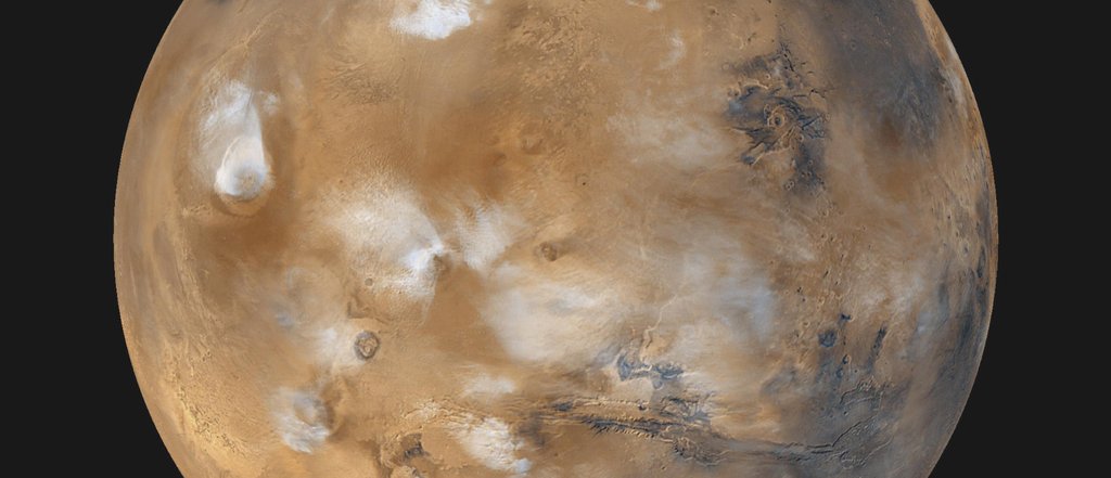 Twelve orbits a day provide NASA's Mars Global Surveyor MOC wide angle cameras a global 'snapshot' of weather patterns across the planet. Here, bluish-white water ice clouds hang above the Tharsis volcanoes.