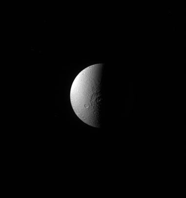 Dione's large crater, Evander, appears here half in shadow, throwing its topography into sharp relief as seen by NASA's Cassini spacecraft.