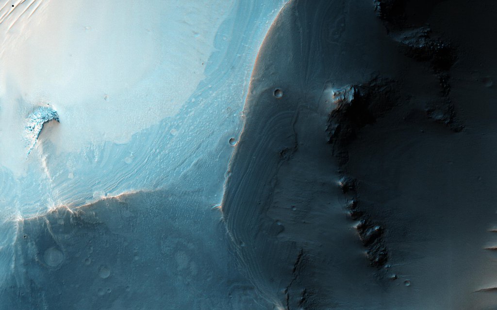 This image shows a set of coalesced collapse pits in western Valles Marineris as seen by NASA's Mars Reconnaissance Orbiter. Fine layers are exposed in the walls of the pits, and in some places those layers are displaced by faults.